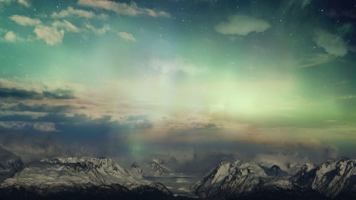 Surreal sky with glowing light and clouds over snow covered mountains.